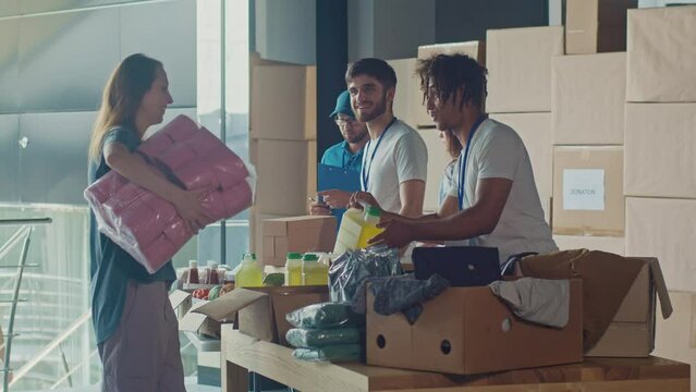 The Concept of Giving:Positive Group of Young Adult Volunteers Serving Humanitarian Aid to Refugees and Immigrants. Humanitarian Aid Charity Workers Serve Meals and Hygiene Products to People in Need.