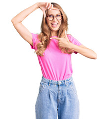 Young beautiful caucasian woman with blond hair wearing casual clothes and glasses smiling making frame with hands and fingers with happy face. creativity and photography concept.