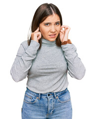 Young beautiful woman wearing casual turtleneck sweater covering ears with fingers with annoyed expression for the noise of loud music. deaf concept.