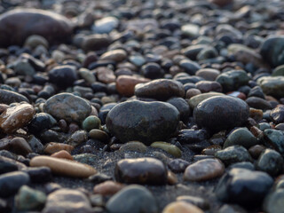 Pebbles on the seashore close-up. Rocky beach. Stones close-up with bokeh. Gray natural background.   Waves and wet pebbles