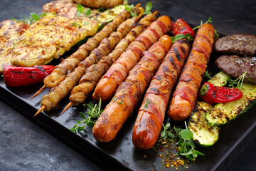 Traditional Grillplatte mit Bratwurst, Hamburger und Steaks zubereitet für eine Sommer Grillparty serviert als close-up auf einem rustikalen Board 