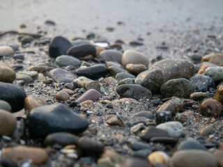 Pebbles on the seashore close-up. Rocky beach. Stones close-up with bokeh. Gray natural background. The concept of rest on the seashore. The Velvet season.  Waves and wet pebbles