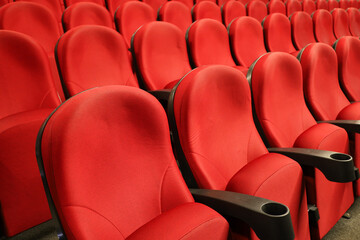 Fototapeta premium Empty cinema hall with red seats. Interior of modern movie theatre, selective focus