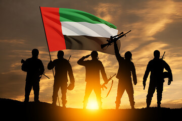 Fototapeta na wymiar Silhouettes of soldiers with the flag of UAE against sunset or sunrise. Concept of national holidays. Commemoration Day.