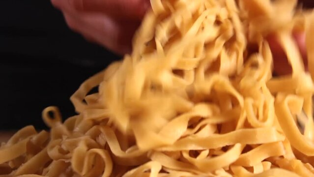 Preparing homemade egg pasta. Female hands raise and throw pasta on the table. High quality FullHD footage