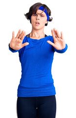 Obraz na płótnie Canvas Beautiful young woman with short hair wearing training workout clothes doing stop gesture with hands palms, angry and frustration expression