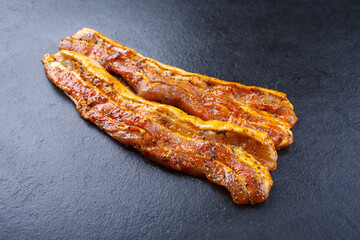 Traditional rohe würzig marinierte Schweinebauch Scheiben zubereitet für eine Sommer Grillparty und angeboten als close-up auf einem schwarzen Board mit Textfreiraum