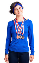 Beautiful young woman with short hair wearing winner medals looking positive and happy standing and smiling with a confident smile showing teeth