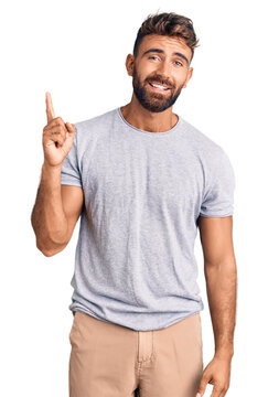 Young hispanic man wearing casual clothes pointing finger up with successful idea. exited and happy. number one.