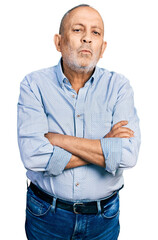 Fototapeta premium Senior man with grey hair and beard with arms crossed gesture looking at the camera blowing a kiss being lovely and sexy. love expression.