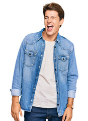 Handsome caucasian man wearing casual denim jacket winking looking at the camera with sexy expression, cheerful and happy face.
