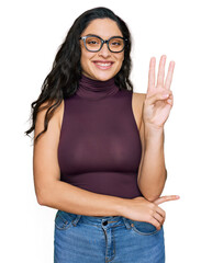 Brunette young woman wearing casual clothes and glasses showing and pointing up with fingers number three while smiling confident and happy.