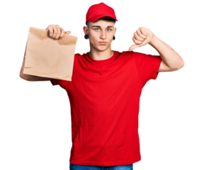 Young caucasian boy with ears dilation holding take away paper bag with angry face, negative sign showing dislike with thumbs down, rejection concept