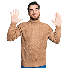 Naklejka premium Young hispanic man wearing casual clothes showing and pointing up with fingers number ten while smiling confident and happy.