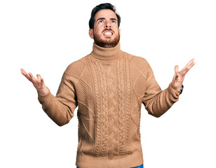 Fototapeta premium Young hispanic man wearing casual clothes crazy and mad shouting and yelling with aggressive expression and arms raised. frustration concept.