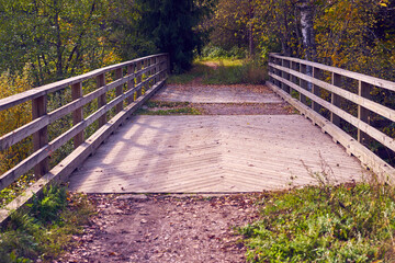Fototapeta premium Wooden bridge over a mountain river in the autumn forest.