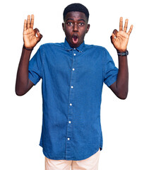 Young african american man wearing casual clothes looking surprised and shocked doing ok approval symbol with fingers. crazy expression