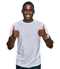 Young african american man wearing casual white t shirt success sign doing positive gesture with...