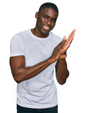 Young African American Man Wearing Casual White T Shirt Clapping And Applauding Happy And Joyful, Smiling Proud Hands Together