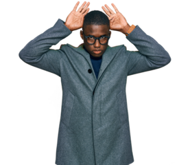 Young african american man wearing business clothes and glasses doing bunny ears gesture with hands palms looking cynical and skeptical. easter rabbit concept.