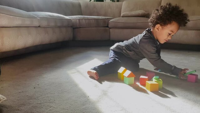 Biracial toddler plays with blocks in living room