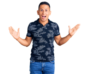 Young handsome latin man wearing casual clothes celebrating victory with happy smile and winner expression with raised hands