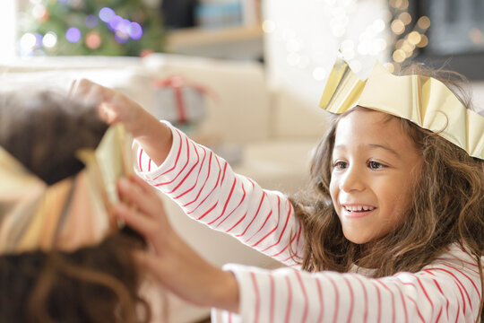 Girl adjusting paper Christmas crown on sister