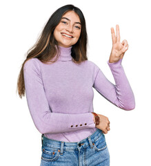 Young beautiful teen girl wearing turtleneck sweater smiling looking to the camera showing fingers...