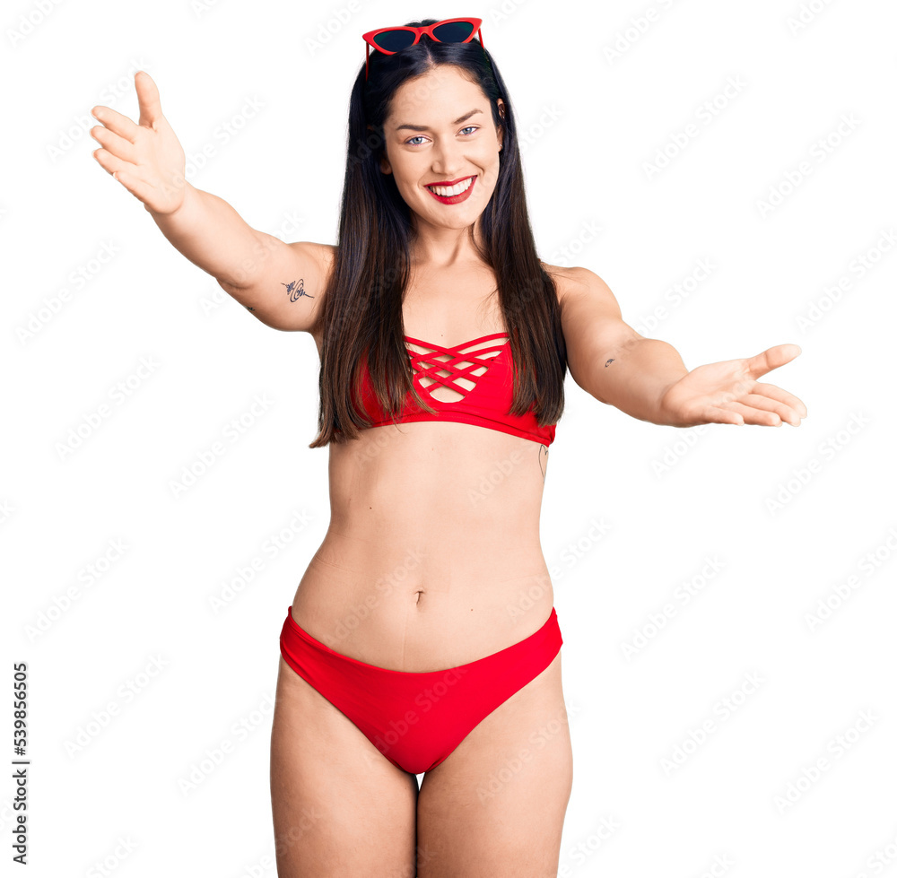 Poster young beautiful caucasian woman wearing bikini looking at the camera smiling with open arms for hug.