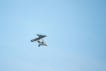 Fototapeta na wymiar Powered paraglider flight. Hobbies and aviation sports. Paraglider against the blue sky.