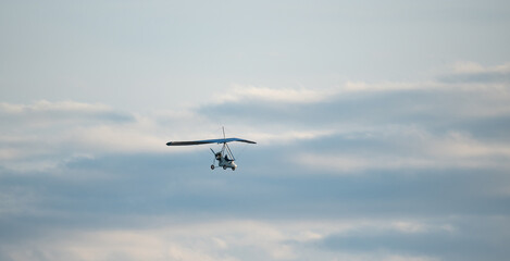 Fototapeta na wymiar Powered paraglider flight. Hobbies and aviation sports. Paraglider against the blue sky.