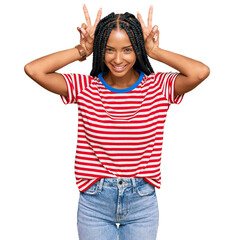 Beautiful hispanic woman wearing casual clothes posing funny and crazy with fingers on head as...
