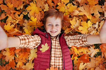 Top view of a boy making selfie on autumn leafs