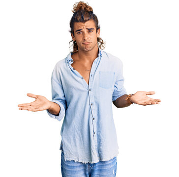Young hispanic man wearing summer style clueless and confused with open arms, no idea concept.
