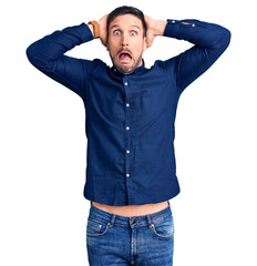 Young handsome man wearing casual shirt crazy and scared with hands on head, afraid and surprised...