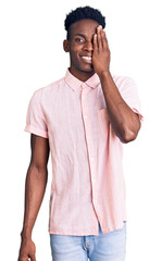 Fototapeta premium Young african american man wearing casual clothes covering one eye with hand, confident smile on face and surprise emotion.