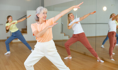 Fototapeta na wymiar Mature adult female dancing with other women during group class in dance center