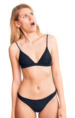 Fototapeta premium Young beautiful blonde woman wearing bikini in shock face, looking skeptical and sarcastic, surprised with open mouth