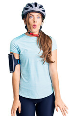 Beautiful caucasian young woman wearing bike helmet scared and amazed with open mouth for surprise, disbelief face