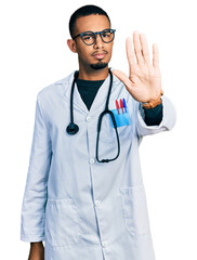 Young african american man wearing doctor uniform and stethoscope doing stop sing with palm of the hand. warning expression with negative and serious gesture on the face.
