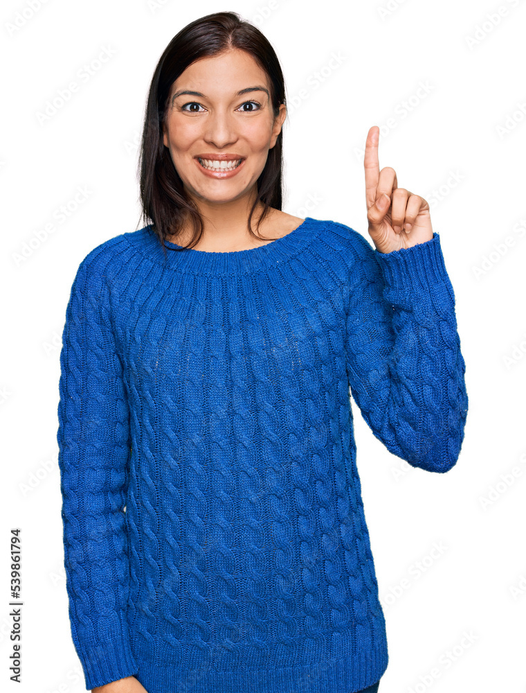 Poster Young hispanic woman wearing casual clothes showing and pointing up with finger number one while smiling confident and happy.