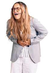 Young beautiful blonde woman wearing call center agent headset with hand on stomach because nausea,...
