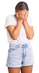 Young beautiful blonde woman wearing casual white tshirt with sad expression covering face with hands while crying. depression concept.