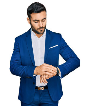 Young hispanic man wearing business jacket checking the time on wrist watch, relaxed and confident
