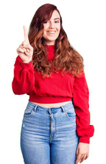 Young beautiful woman wearing casual winter sweater showing and pointing up with finger number one while smiling confident and happy.