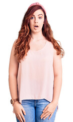 Fototapeta premium Young beautiful woman wearing casual clothes and diadem scared and amazed with open mouth for surprise, disbelief face