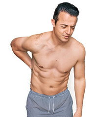 Fototapeta premium Handsome young man wearing swimwear shirtless suffering of backache, touching back with hand, muscular pain