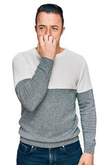 Handsome young man wearing casual winter sweater looking stressed and nervous with hands on mouth biting nails. anxiety problem.