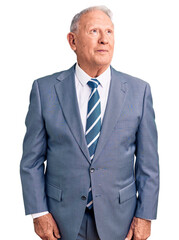 Senior handsome grey-haired man wearing elegant suit smiling looking to the side and staring away thinking.