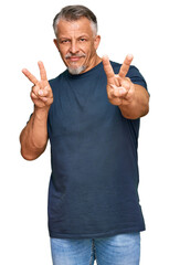 Middle age grey-haired man wearing casual clothes smiling looking to the camera showing fingers doing victory sign. number two.